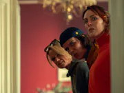 Three white women peeking round a door with a suspicious look on their faces