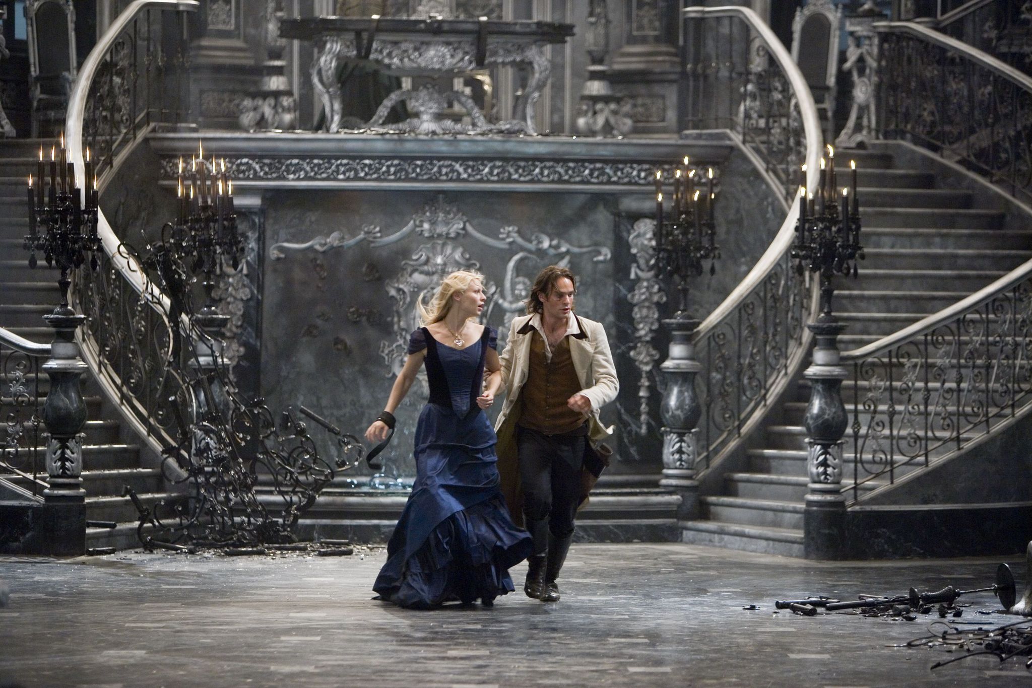 A white man and woman walking towards the camera with two connecting staircases behind them.