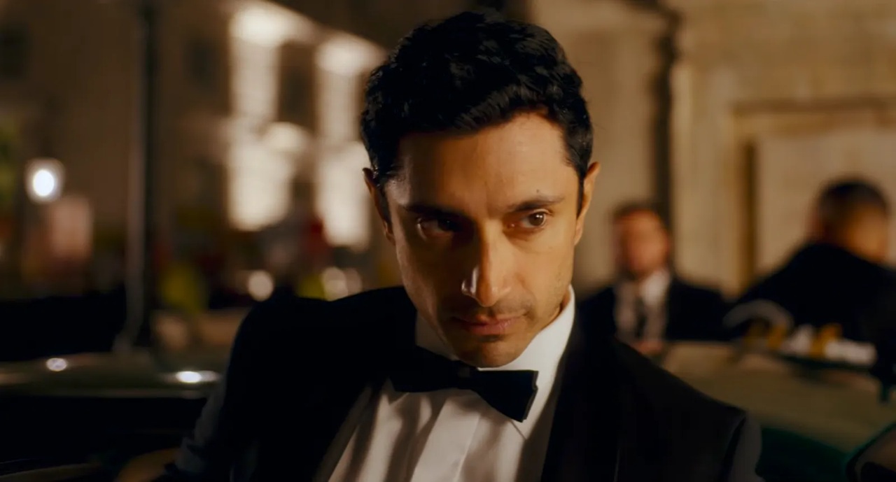 A British Pakistani man in a black tuxedo and bowtie stepping out of a fancy car, with a cool smouldering look on his face