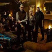 A white family stands around a fireplace looking ominously at the camera.