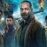 Group of men and women stand in front of a large shipping rig