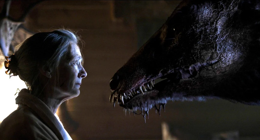 A woman stands face to face with a murderous looking deer in her house.