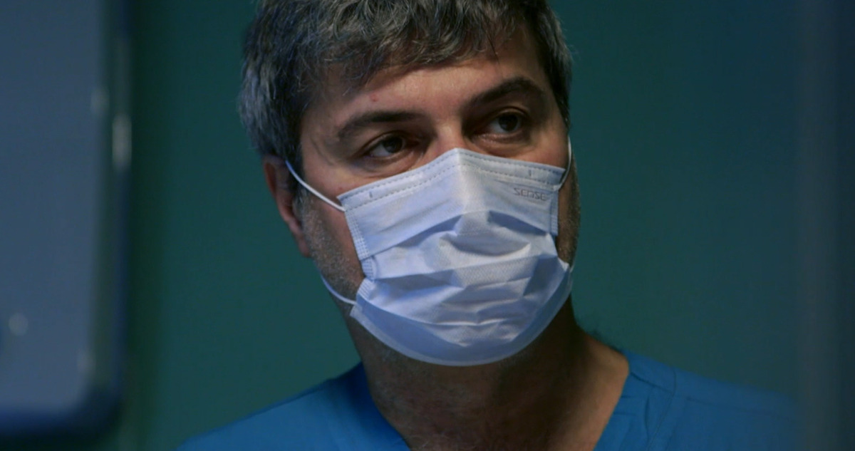 A man wearing a mask and hospital scrubs.