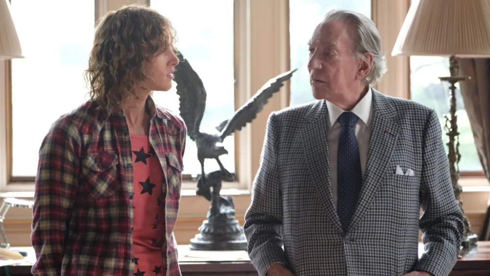 Two white men, one old and one young, stand facing each other.