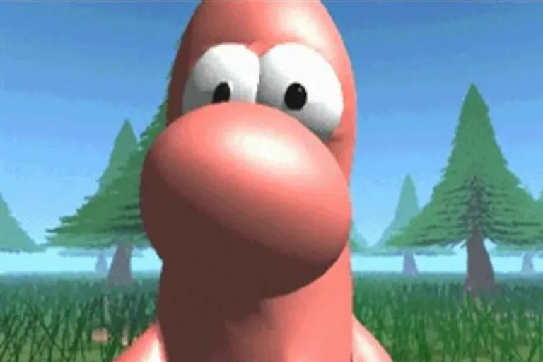 A close-up of a pink worm-shaped creature with eyes and a big nose, in a grassy area