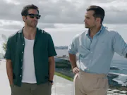 Two men standing on the balcony of a beach house