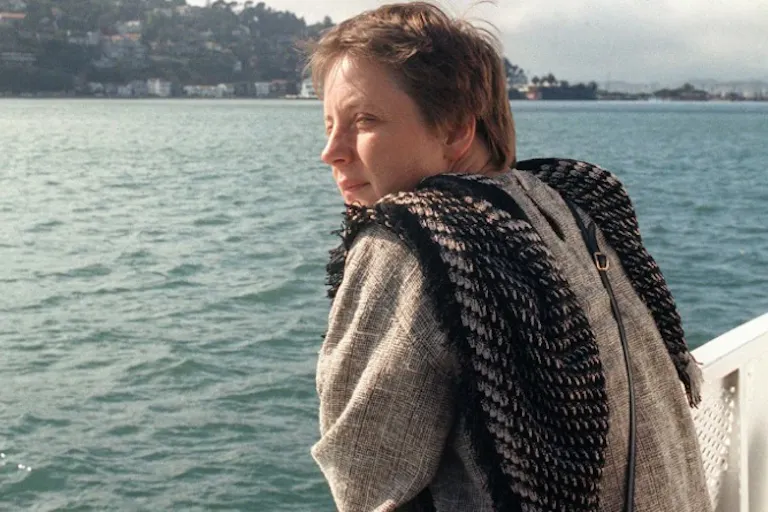 A white woman leaning on a railing looking out onto the blue sea
