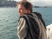 A white woman leaning on a railing looking out onto the blue sea