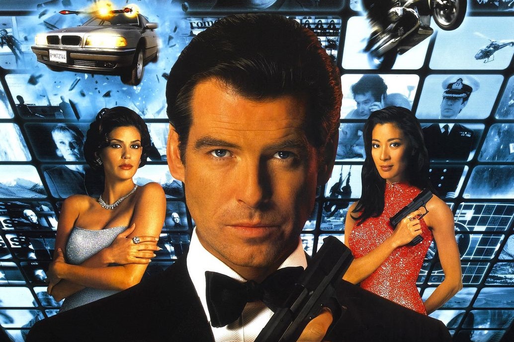 A white man in a black tuxedo in the foreground, with two young women in the background wearing dresses