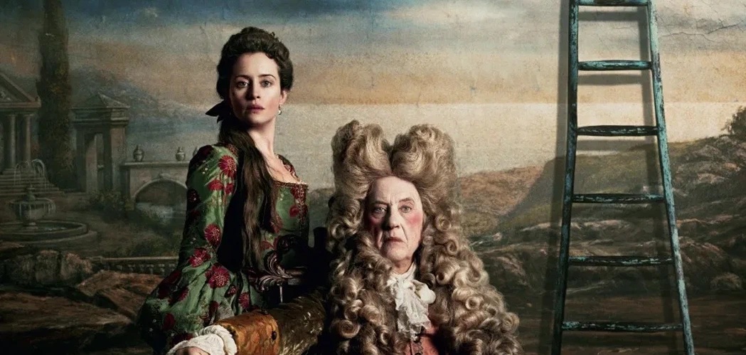 A late 30's white woman with dark hair standing next to a seated early-60s white man in front of a sunset backdrop. Both of which are in 18th century England attire, with the man wearing a large white wig