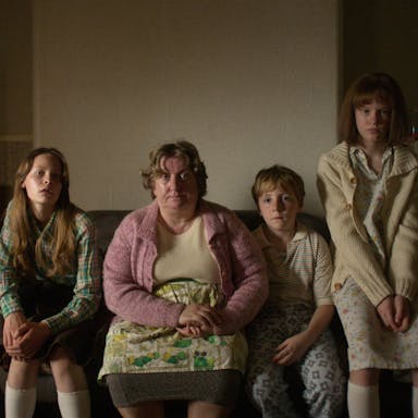A white working class family in the 1970s sitting on a sofa in their muted house