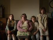 A white working class family in the 1970s sitting on a sofa in their muted house