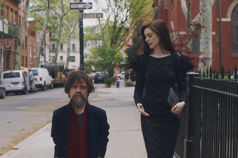 A brunette white woman and a dark haired with greys white man walk down a street