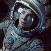 Close up of a white woman in an astronaut suit looking serious