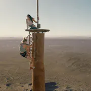 Two women climb on top of an abandoned radio tower.