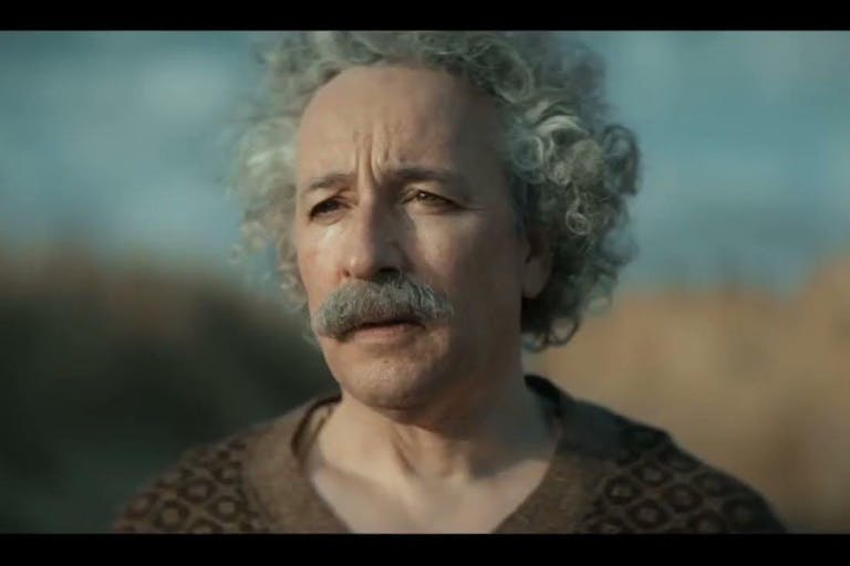 An older white man with big curly white hair and a thick grey moustache looking forlorn  