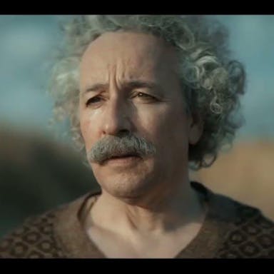 An older white man with big curly white hair and a thick grey moustache looking forlorn  