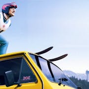 A man skies on top of a yellow van as another man drives looking out of the window.