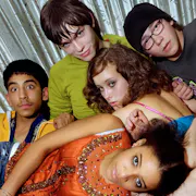 A group of young people tangled up and laying on top of each other looking at the camera