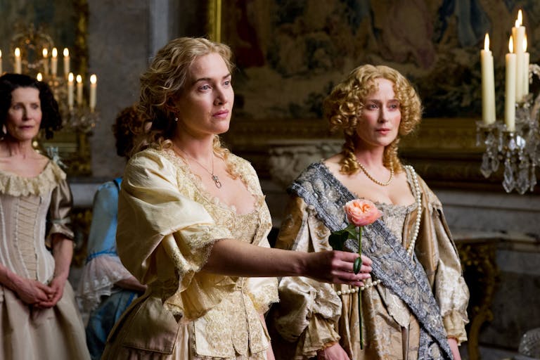 A blonde woman in expensive period clothing, holding out a pink rose, flanked by other women 