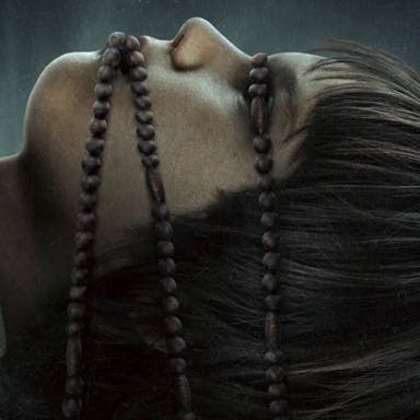 Spooky image of a young person with rosary beads wrapped around eyes and mouth
