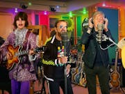 A colour recording studio with four white men, two real life older men (Ringo and Paul McCartney) flanked by digital young men with guitars (George Harrison, and John Lennon)
