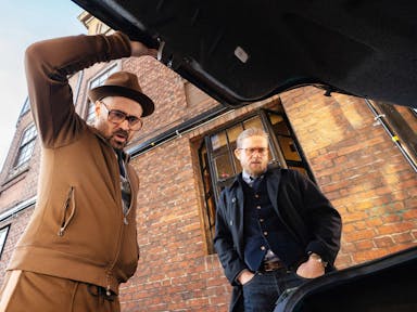 Two men looking menacingly in a car boot