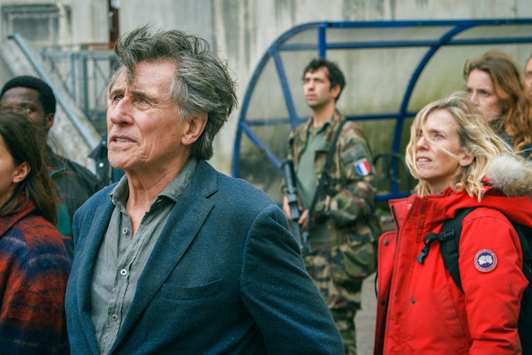 Group of people look towards the sky with a worried look on their faces