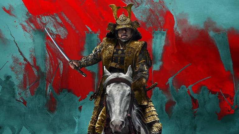 An older Japanese man in elegant armour sitting on a white horse brandishing a sword, with red and blue background silhouette of other soldiers