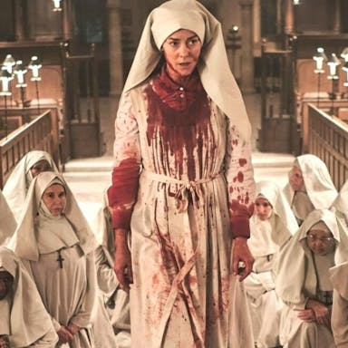 Group of nuns in white habits in a church, one of them covered in blood