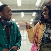 A young man and a woman walk through a shopping centre smiling at each other