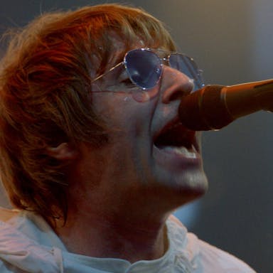 Man in sunglasses sings into a microphone.