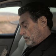 A middle aged white man sitting in a car loading a gun