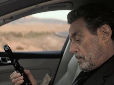 A middle aged white man sitting in a car loading a gun