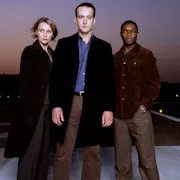 A white woman, white man and Black man stand looking mysterious and serious