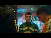 Two young white Irish men in striped trackie tops in a pub playing a fruit machine