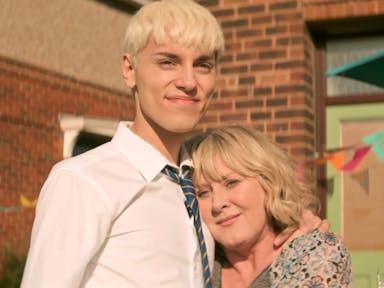 A tall blond male teenager standing next to his mum, leaning her head against his chest smiling 