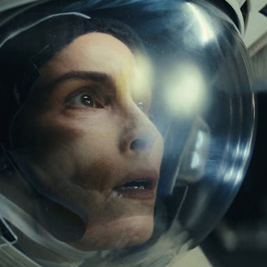 Close up of a white woman in space in an astronaut's clothing and helmet looking shocked