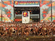 Large colourful stage with 'Woodstock 99' banner and a sea of muddy festival goers
