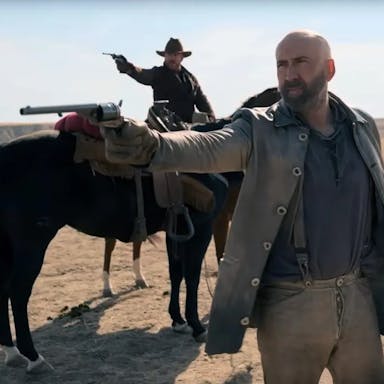 A white man in old west clothing pointing an old style pistol, as another white man wearing a cowboy hat, riding a horse, also points a gun in the same direction 