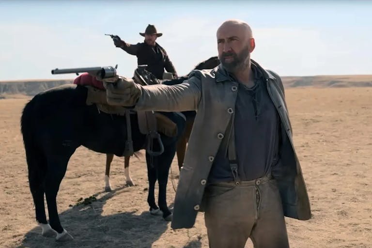 A white man in old west clothing pointing an old style pistol, as another white man wearing a cowboy hat, riding a horse, also points a gun in the same direction
