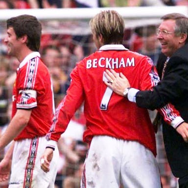 Two male footballers in red and white kit, one with 'Beckham 7' on back of shirt, and a football manager on the football field celebrating 