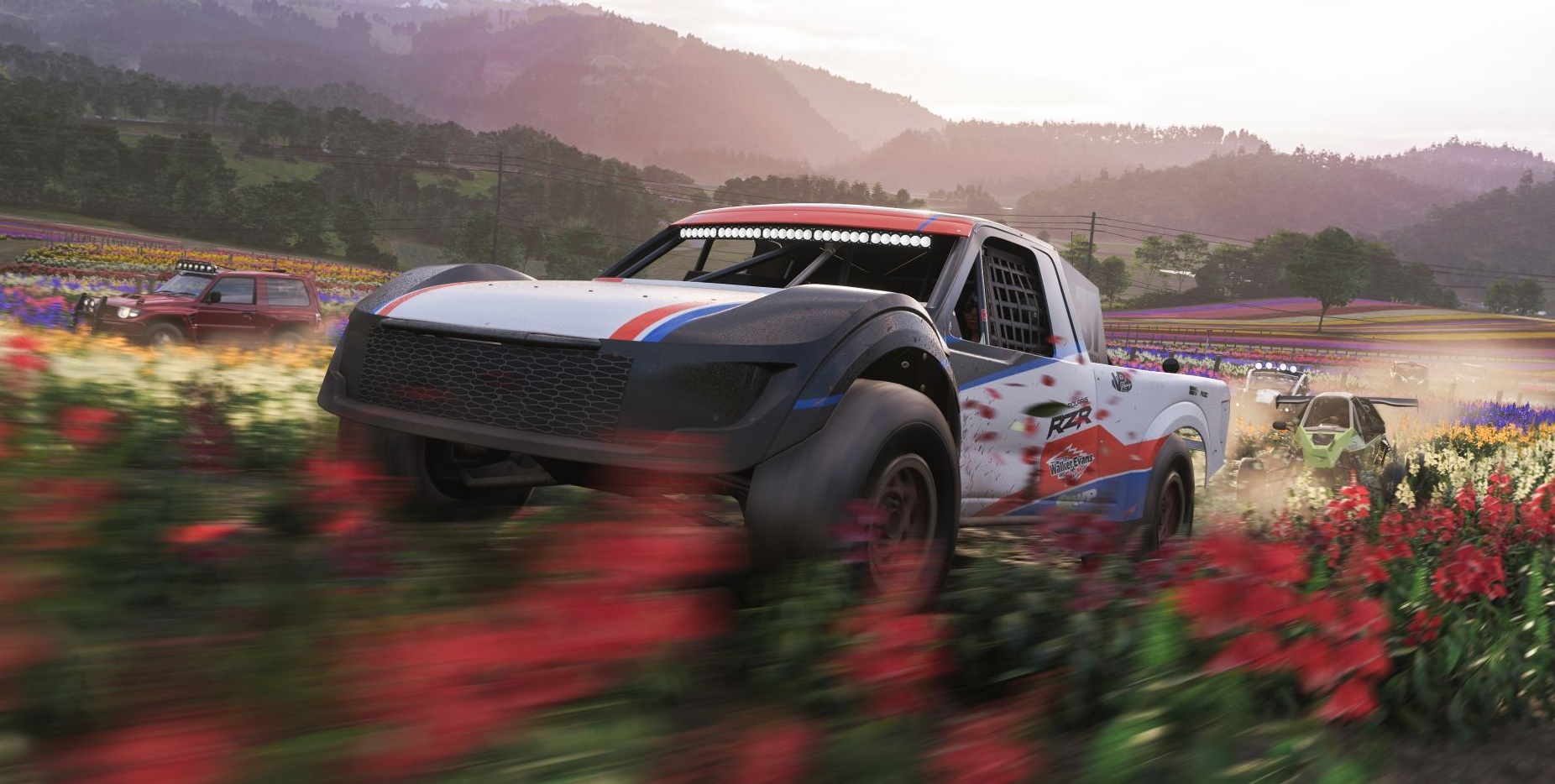 A white red and blue car driving fast through a field of red flowers