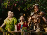 From left to right: A blonde haired fairy woman, a young girl, and a tin man. All standing in a tree