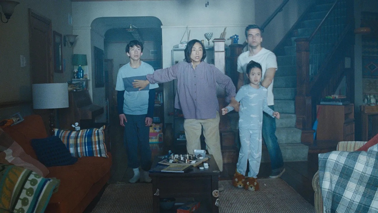 A mum, dad, and two children in their basement, illuminated by a blue light, all with a scared look on their face