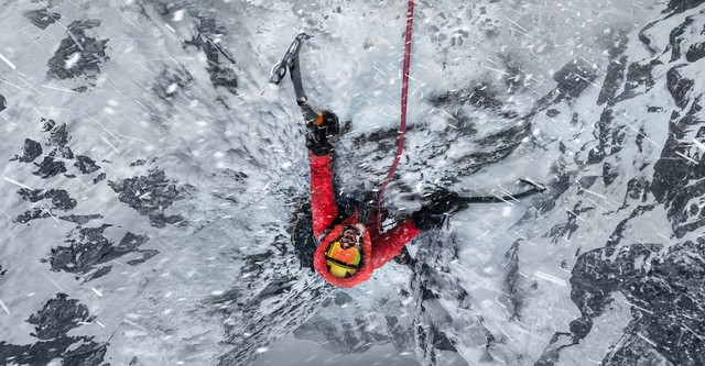 A man midway through climbing a snowy mountain