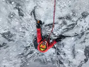 A man midway through climbing a snowy mountain