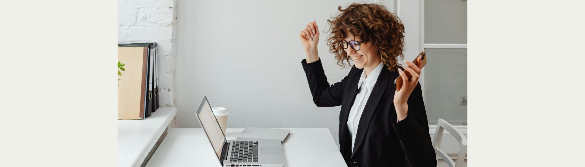 Een vrouw juicht en lacht. Voor haar staat een opengeklapte laptop.
