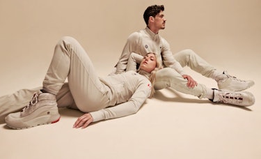 Paul Poirier and Piper Gilles posing on the ground, wearing all-white lululemon x Team Canada gear.