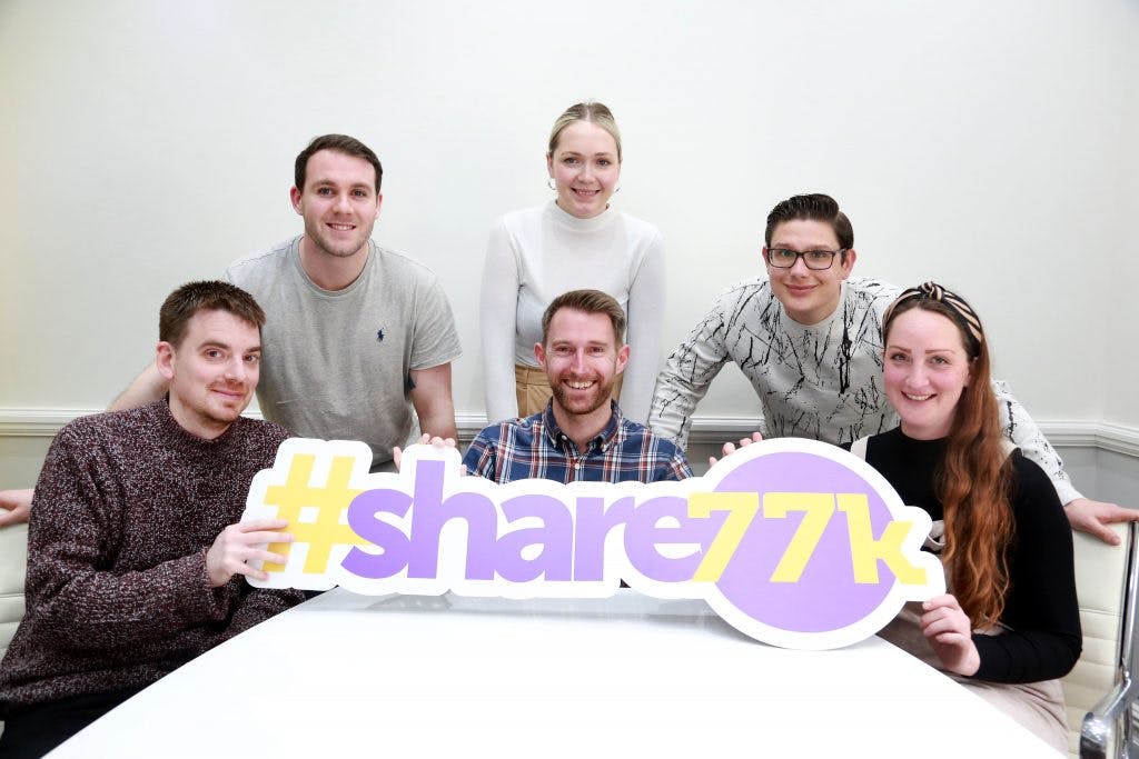 Photo of team holding #share77k sign